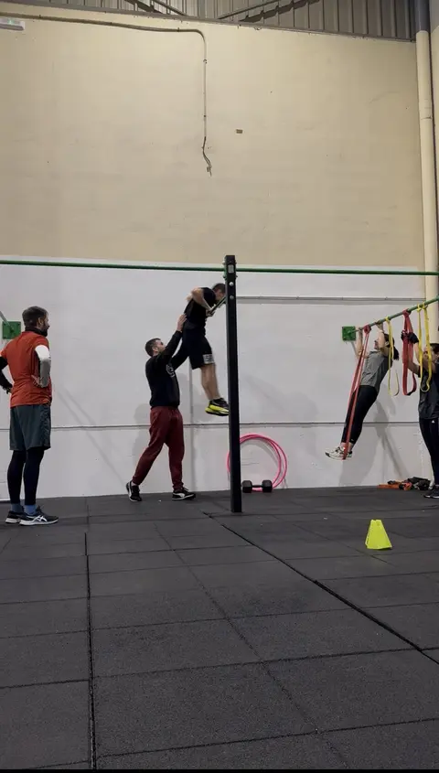 Entrenamiento de calistenia con progresiones y apoyo del monitor.