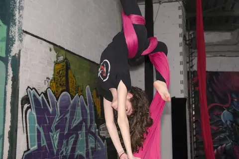 Alumna realizando una figura de apertura en telas aéreas.